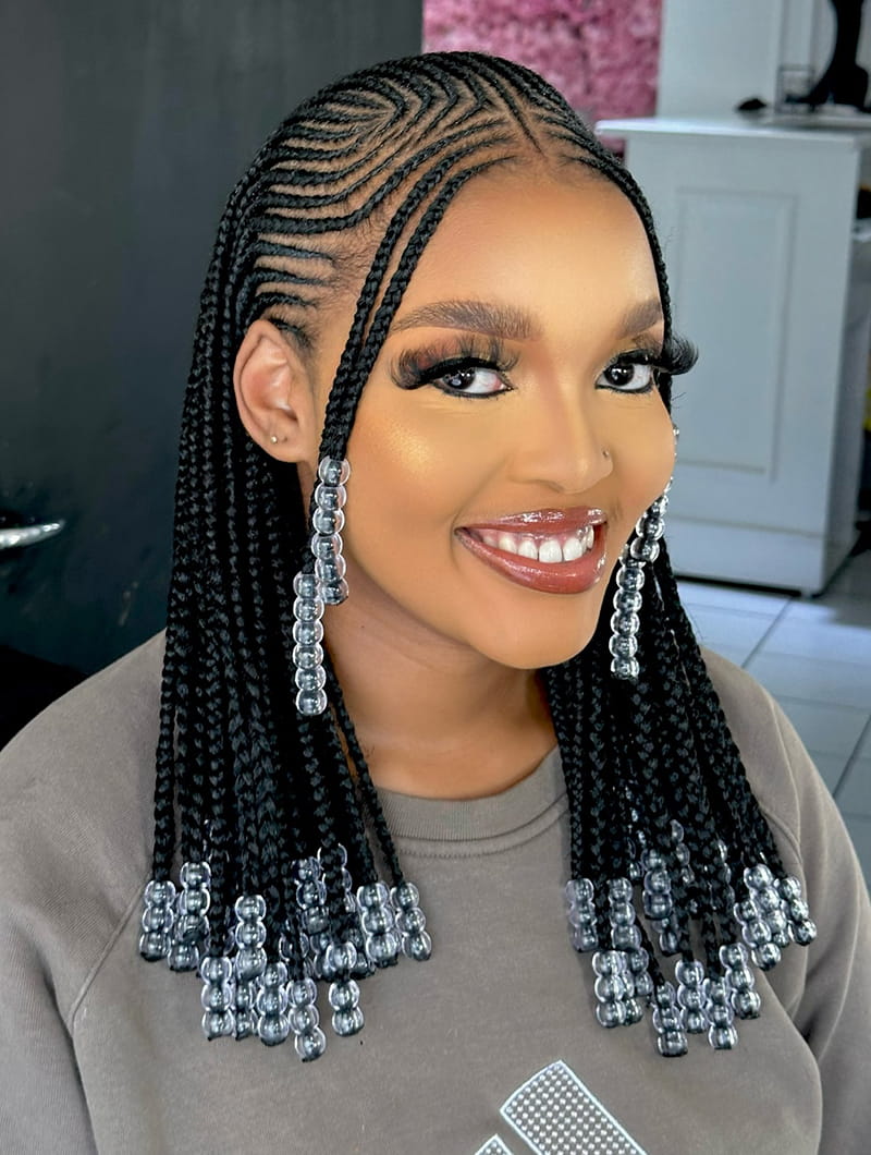 An African American Woman is wearing a fulani brads hairstyle. The braids are adorned with beautiful glass beads.