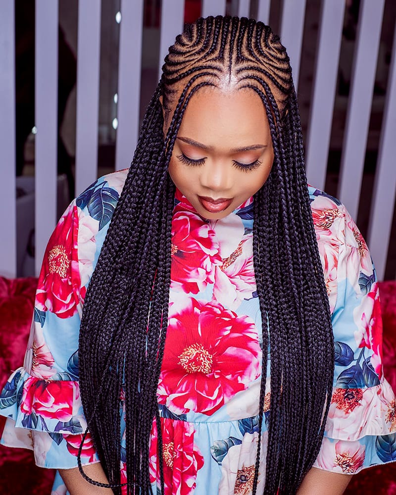 A woman wearing complicated Fulani-Inspired Cornrows. The Cornrow style have some braided bangs in the front. And the whole style is framing her face beautifully.