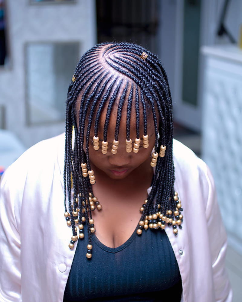 An African American woman is wearing tribal braids, beads and bangs Hairstyle.