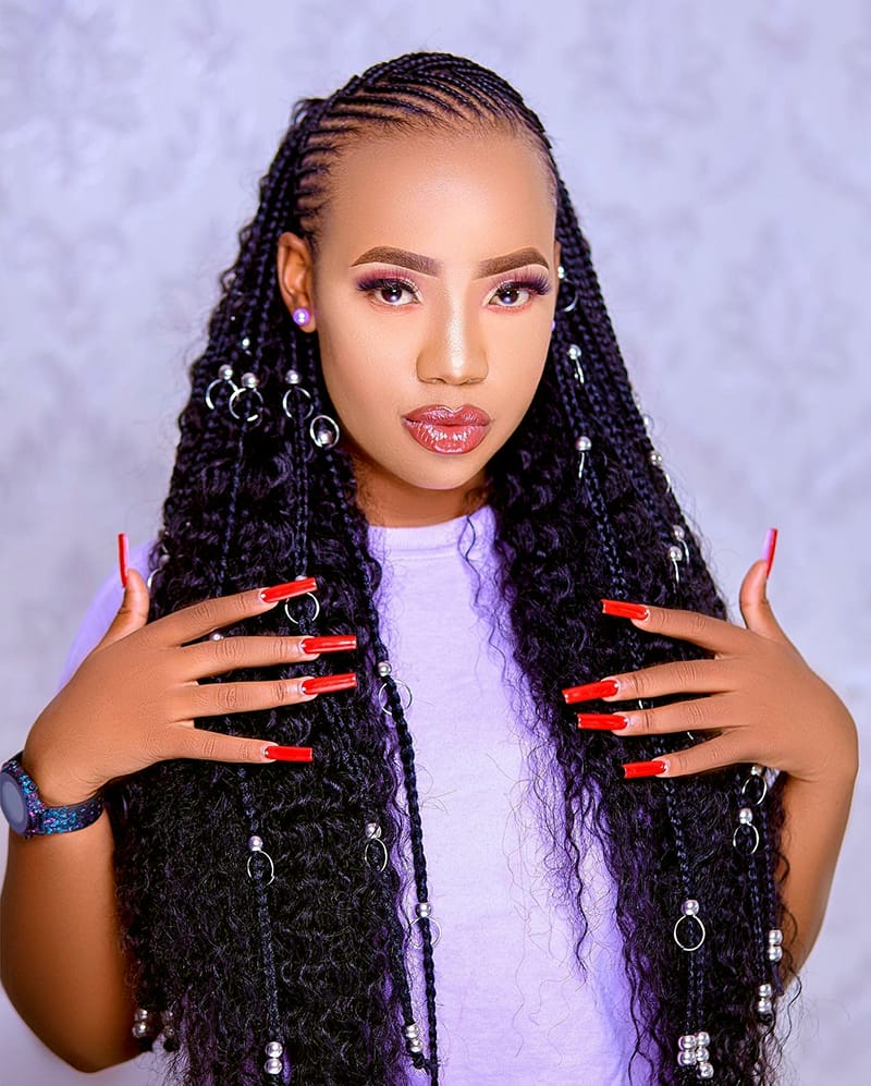 Woman wearing a lovely hairstyle with Fulani Braids. The Braids are adorned with beautiful rings. At the same time, the braids are supported with loose curls that has made it goddess braids.